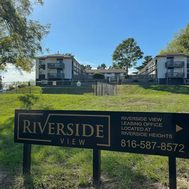 Riverside View Apartment Complex A sign for Riverside View in front of a two-story apartment building surrounded by greenery.