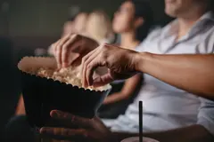 Picture of people in a movie theater eating popcorn