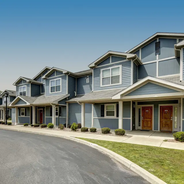 Row of modern townhouses with a curved driveway and greenery.