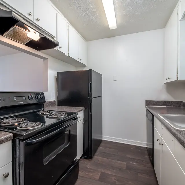 Prospect Heights A kitchen with white cabinets, hardwood-style flooring, a window, black appliances, and a serving window.