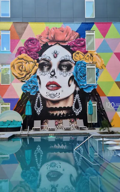 A wall-painted mural overlooking the community pool at 120 Ninth Street with lounge chairs in pool along with trees giving natural shade.