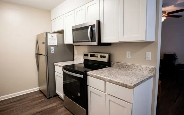 Summit at 501 Compact kitchen featuring stainless steel appliances, white cabinets, and granite countertops. Bright and modern design.
