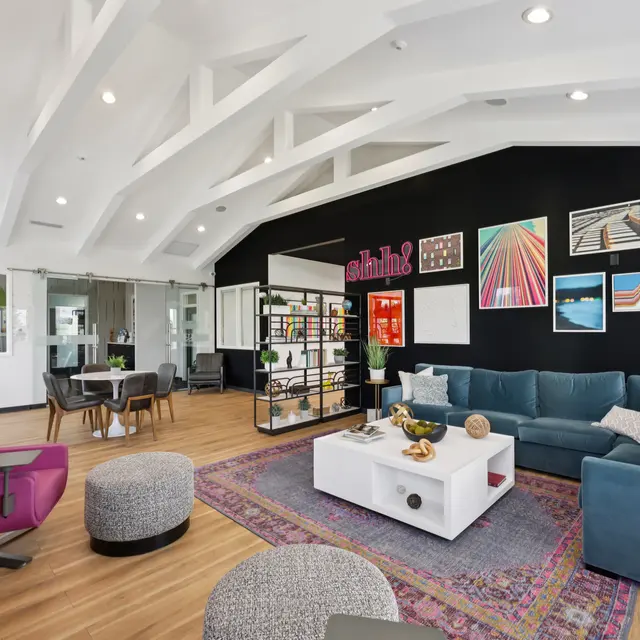Modern Cozy Living Room Interior A modern living room featuring a turquoise sectional sofa, colorful artwork on a black wall, and stylish furniture. The space has a high ceiling with exposed beams and a cozy atmosphere created by a mix of furnishings.