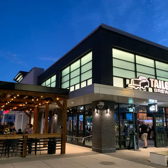 Exterior view of Tailgate Brewery at night featuring a modern building design and outdoor dining area.