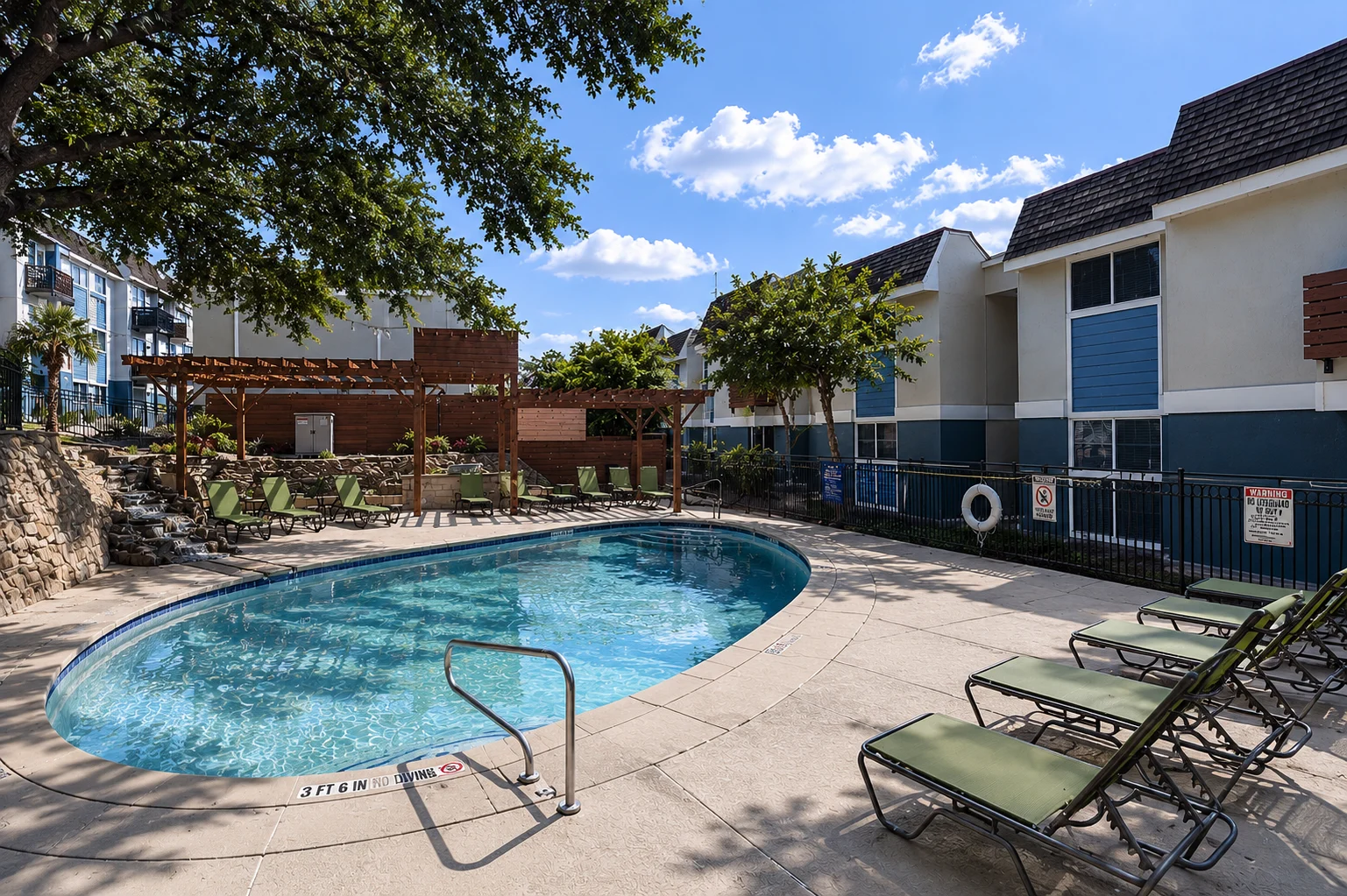 Relaxing Pool Area A swimming pool area featuring a turquoise pool surrounded by lounge chairs and greenery, with a backdrop of residential buildings under a clear blue sky.