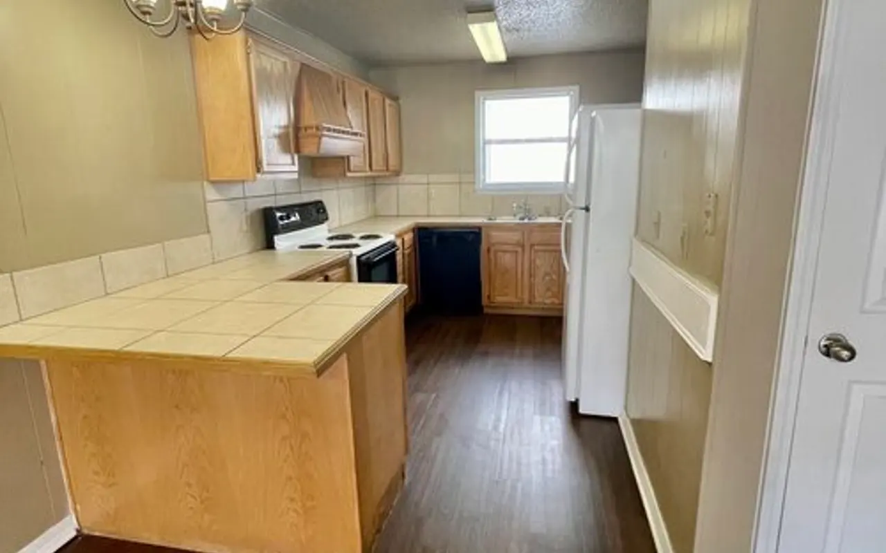 Modern Kitchen Interior A spacious kitchen featuring wooden cabinets, white appliances, and a tiled island with a chandelier above.