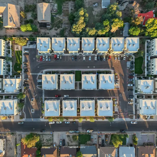 Aerial View of Residential Complex Aerial view of a residential complex featuring multiple buildings arranged in a grid pattern, with parking spaces and surrounding greenery.