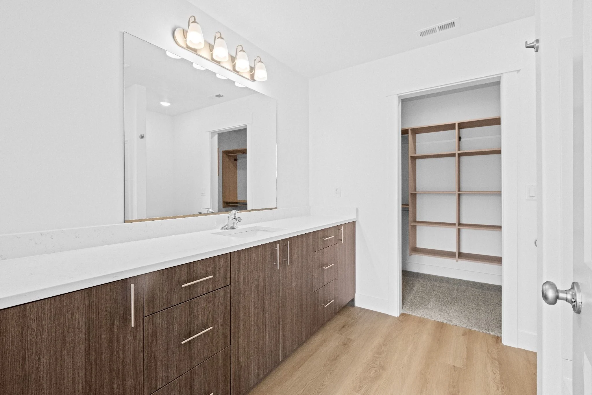 Spacious modern bathroom with wooden cabinetry and a large mirror.