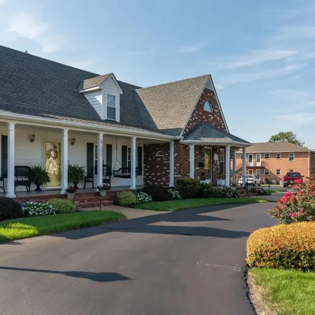 A charming house with a porch, featuring a well-maintained garden and landscaped yard, on a clear sunny day.
