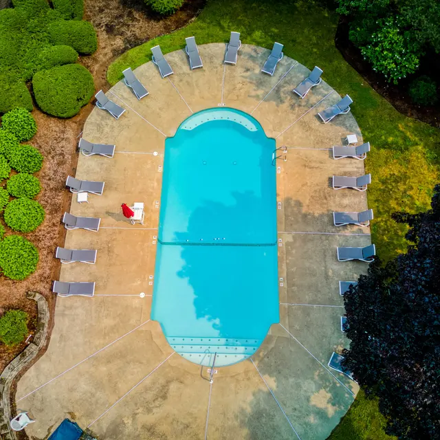 Aerial view of a swimming pool surrounded by lounge chairs and landscaped greenery.