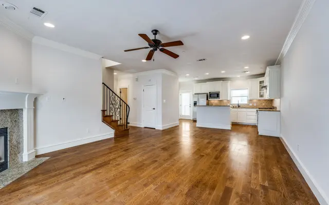 Spacious Living Room with Open Kitchen Interior shot of a spacious living room featuring hardwood floors, a ceiling fan, and open kitchen layout.