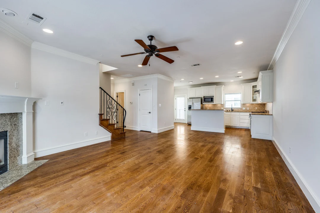 Spacious Living Room with Open Kitchen Interior shot of a spacious living room featuring hardwood floors, a ceiling fan, and open kitchen layout.