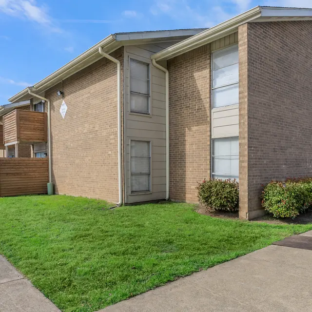 Apartment Complex Exterior Exterior view of a two-story apartment complex with grassy areas and concrete pathways.