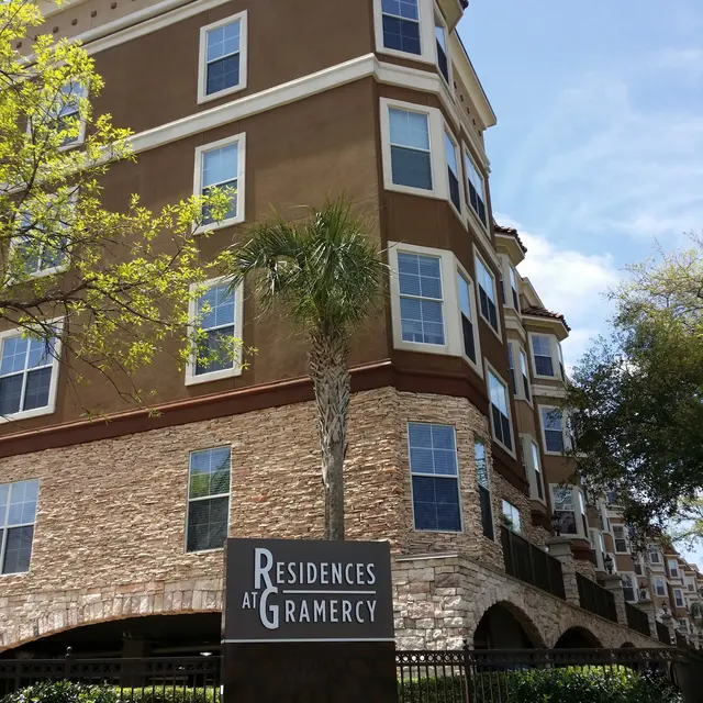 Exterior view of the Residences at Gramercy apartment building with palm trees and blue sky.