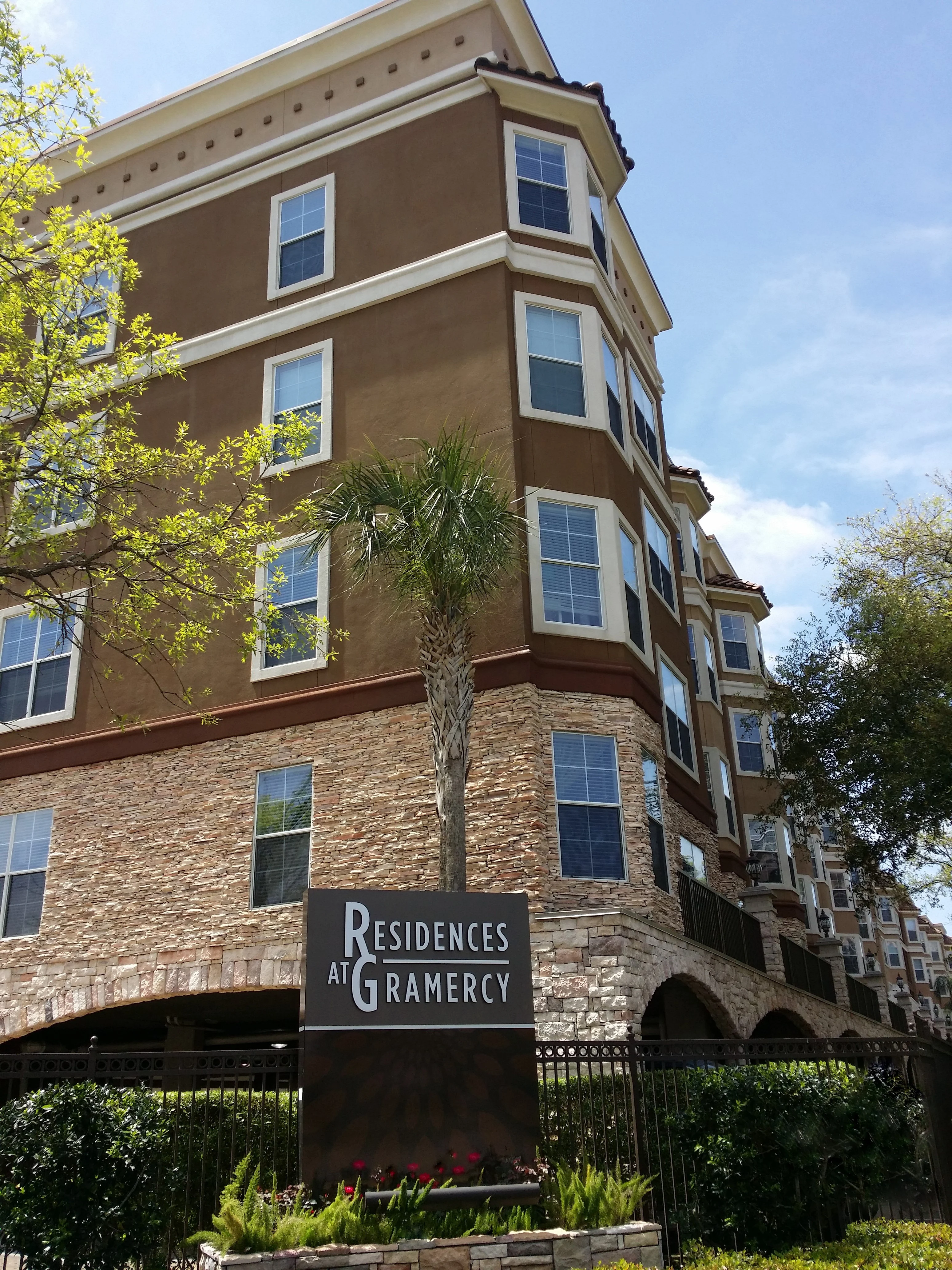 Exterior view of the Residences at Gramercy apartment building with palm trees and blue sky.