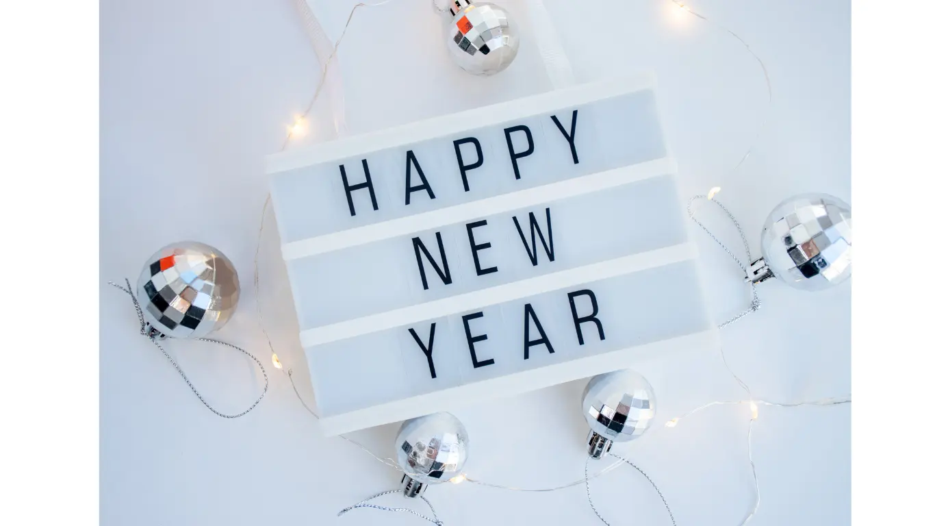 A lightbox displaying the message 'HAPPY NEW YEAR' surrounded by decorative silver disco balls and fairy lights.