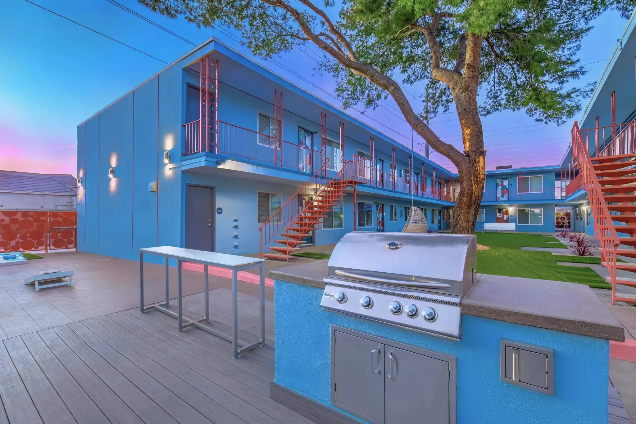 An outdoor space featuring a barbecue grill and modern apartment buildings in the background.