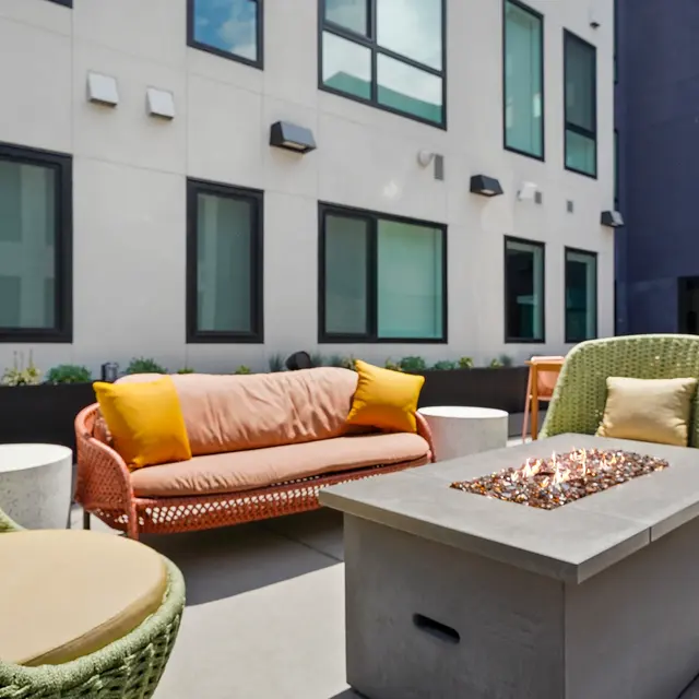 A stylish outdoor lounge area featuring comfortable seating and a fire pit.