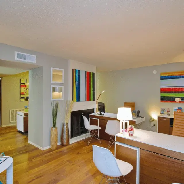 A modern office reception area featuring a desk, chairs, and colorful wall art.
