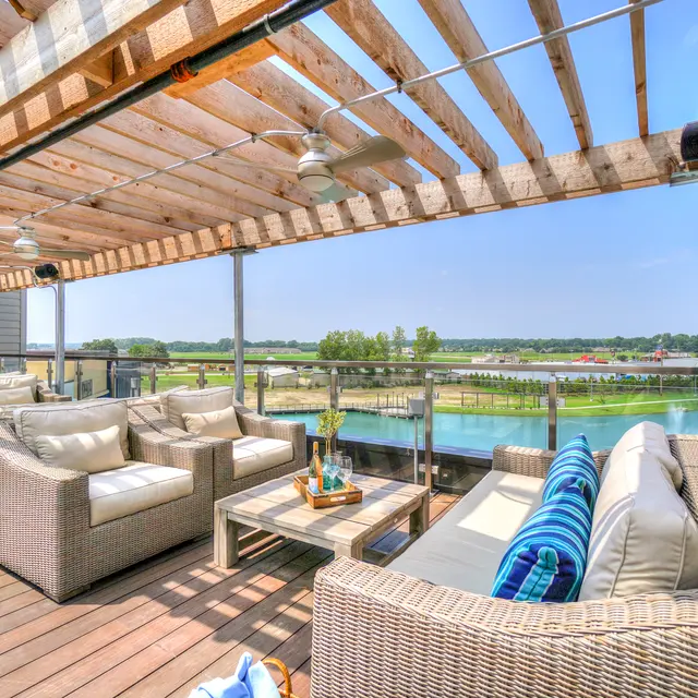 A spacious rooftop lounge area with comfortable seating and a view of a serene body of water.