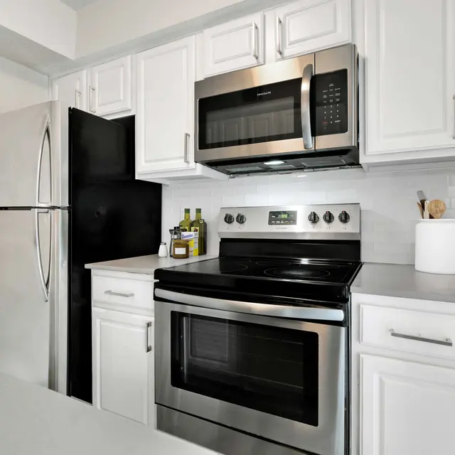Kitchen with stainless steel appliances, white cabinetry, and grey countertops