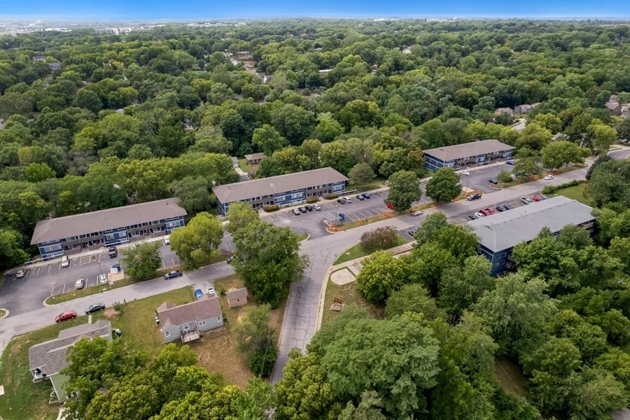 Aerial view of an apartment complex surrounded by lush greenery and trees.