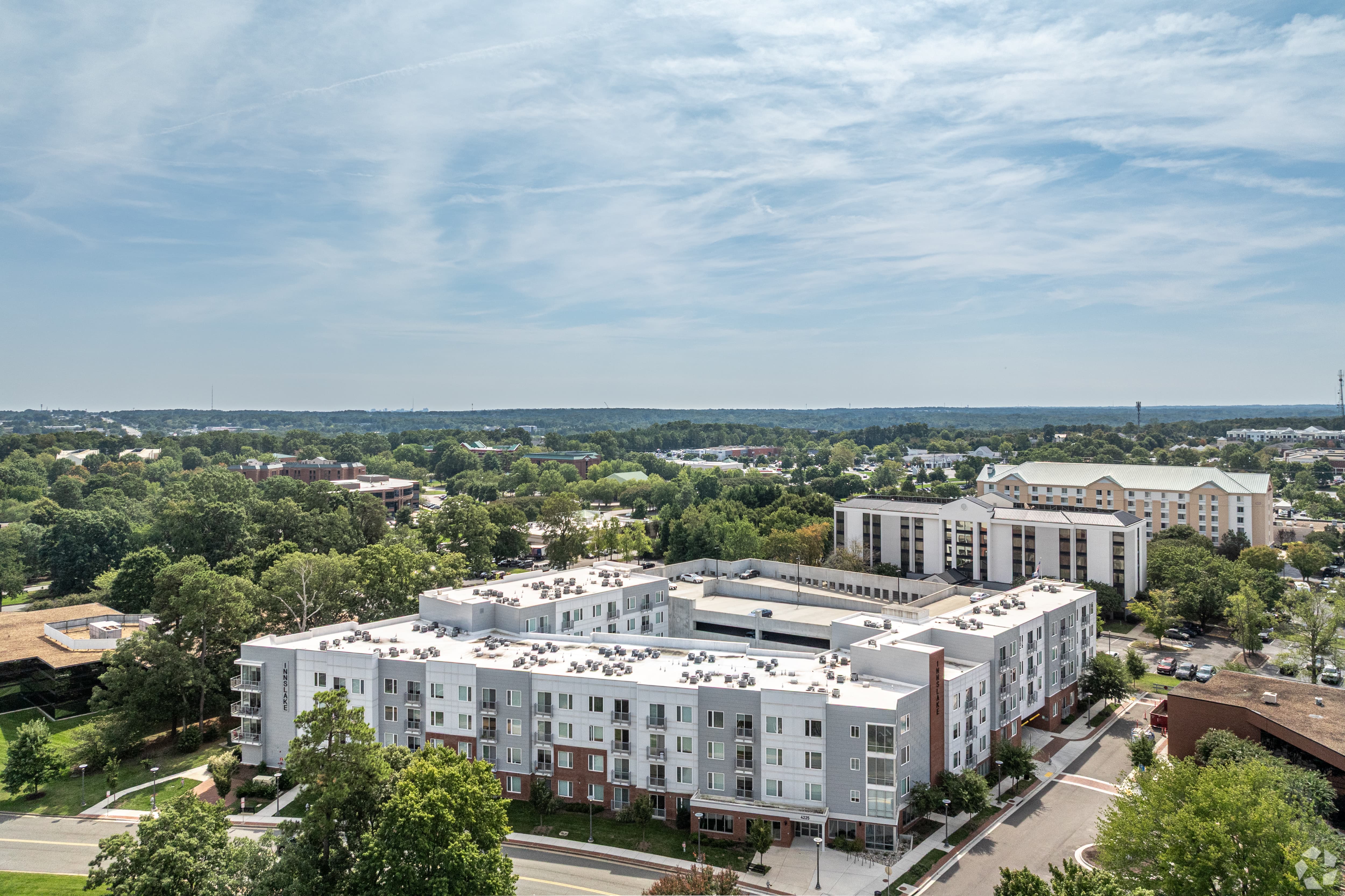Aerial View of Modern Apartments Aerial view of modern multi-story apartments surrounded by green trees and other buildings.