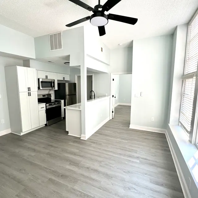 Spacious and modern apartment interior featuring an open layout, grey flooring, and large windows for natural light.