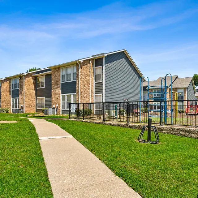 View of a multi-unit apartment complex with a playground in the background