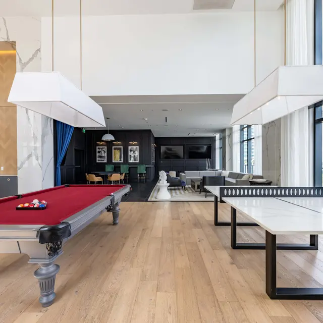 A modern living space featuring a pool table, large windows with natural light, and contemporary furniture.