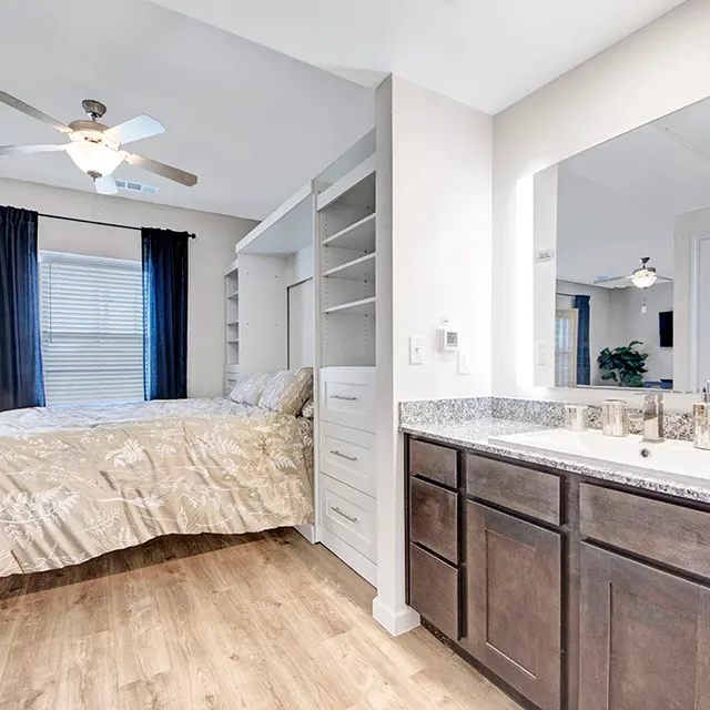 Modern Bedroom and Bathroom Design A modern bedroom with a bed, bookshelves, and adjacent bathroom area featuring a double sink and mirror.