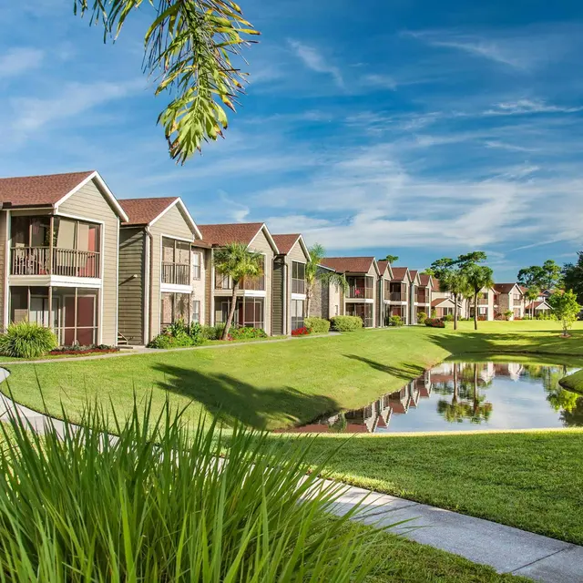 Venice Park Apartments exterior with private patios and a scenic pond view.