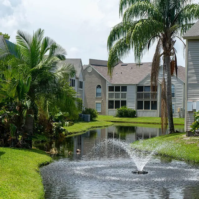 Bradenton Reserve's river with a small water fountain in between apartment buildings and trees. 