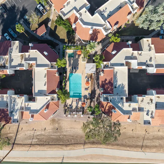 Aerial view of a residential apartment complex featuring multiple buildings arranged around a central pool area.