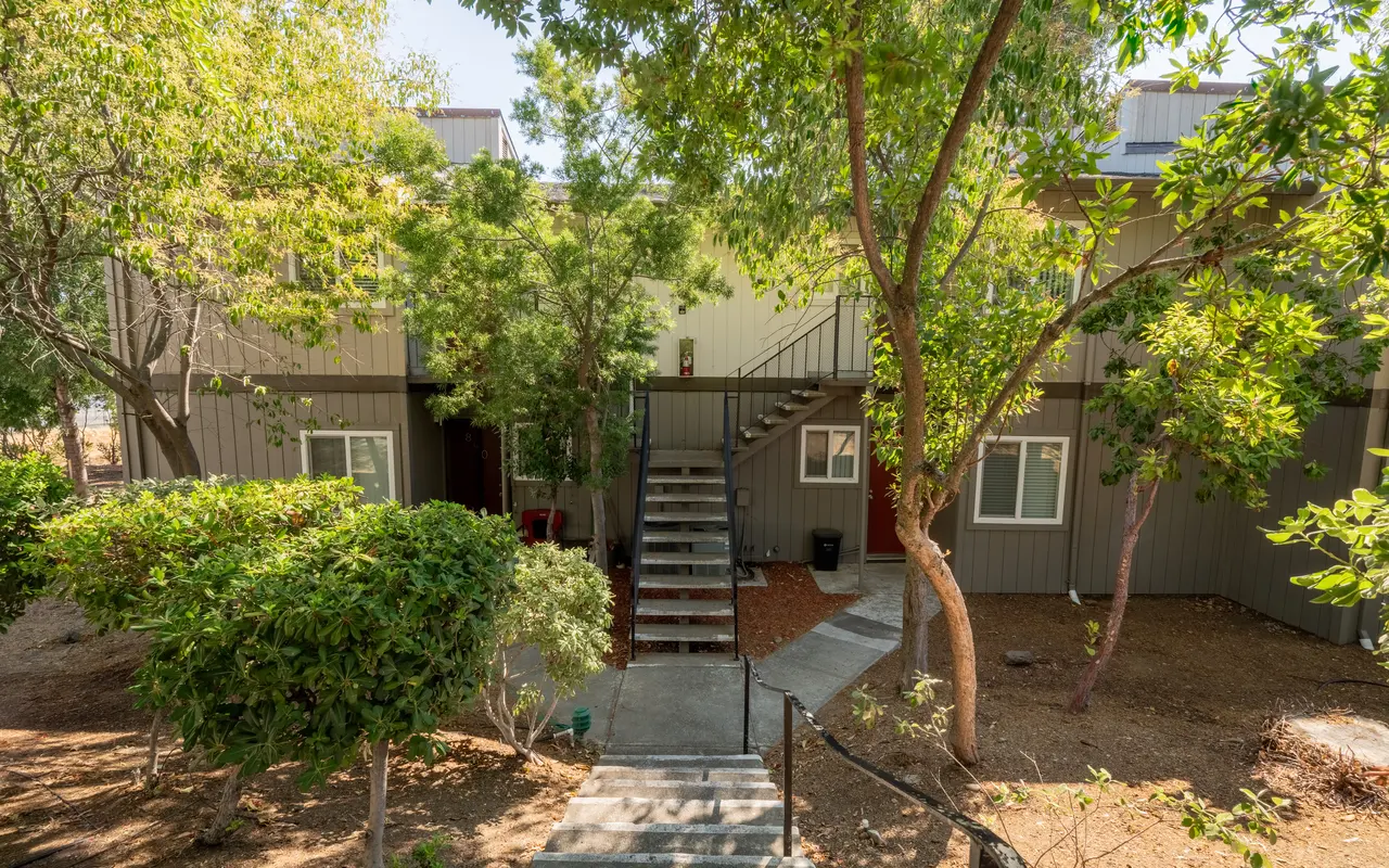 A view of an apartment complex featuring staircases and greenery surrounding the buildings.