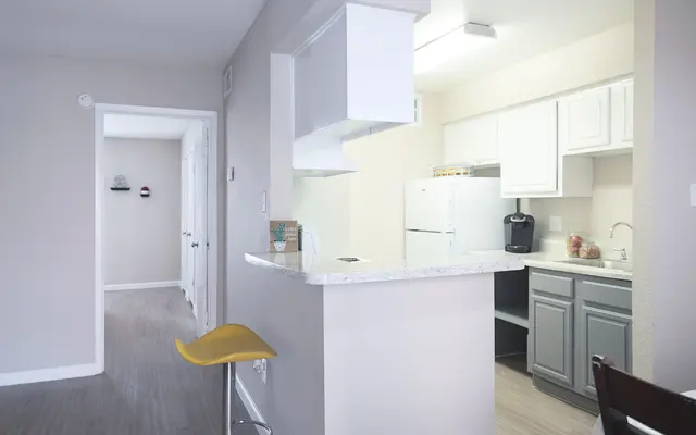 View of a modern apartment interior with a kitchen and seating area.
