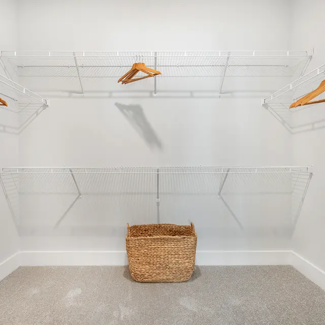 A clean and organized empty closet with wire shelving and a woven basket on the floor.