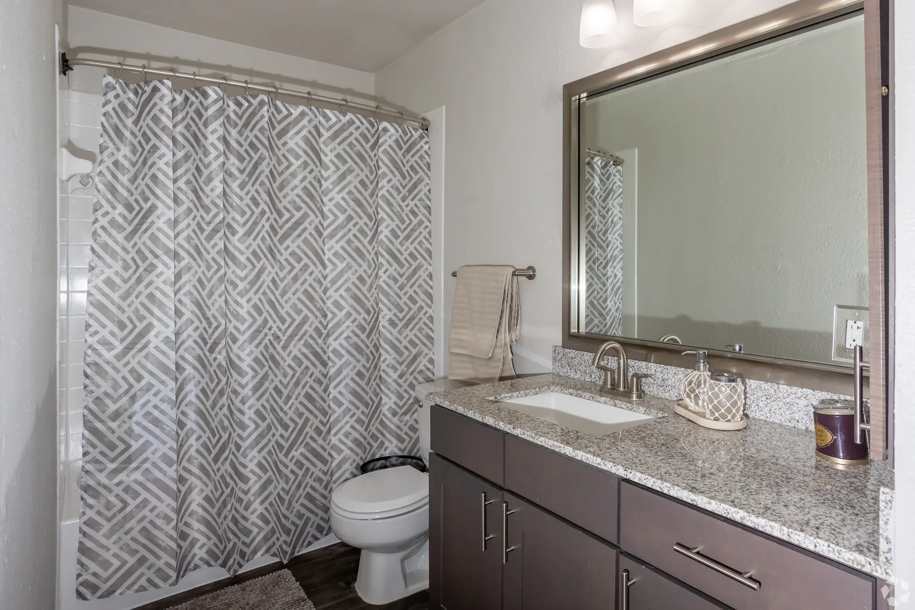 Modern Bathroom Design A modern bathroom featuring a shower with a patterned curtain, a granite countertop, a large mirror, and a toilet.