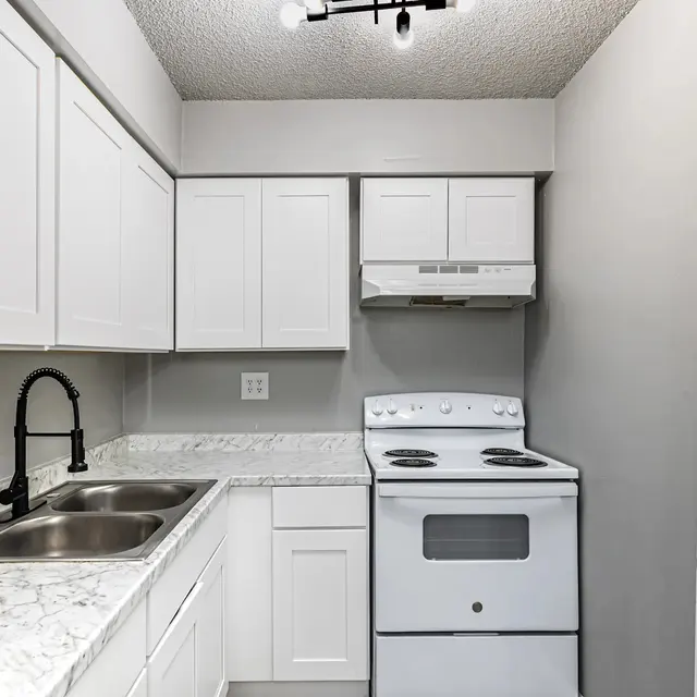 Modern Kitchen Interior A modern kitchen featuring white cabinets, a gray wall, and a white stove with an overhead microwave.