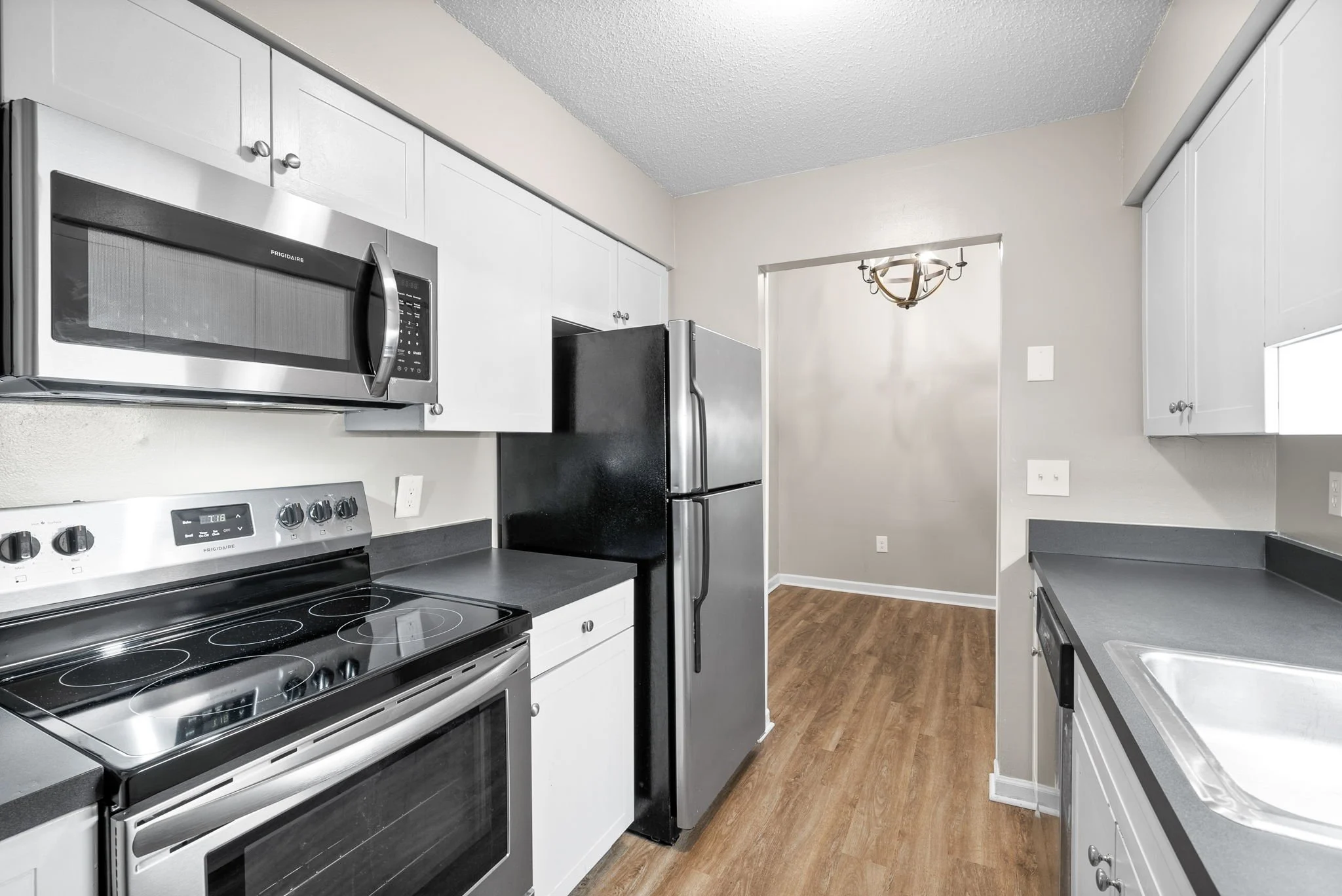 Modern Kitchen Design A modern kitchen featuring stainless steel appliances, light gray cabinets, and wooden flooring. The space includes an oven, microwave, and refrigerator.