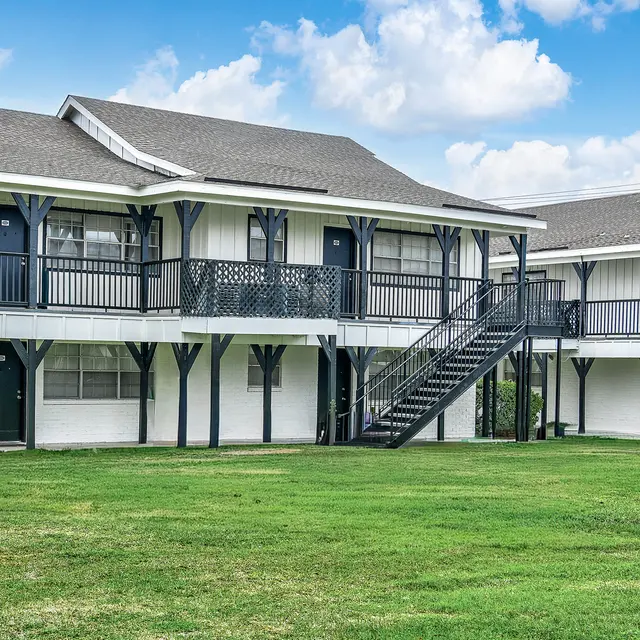Exterior view of a two-story hotel building with a green lawn and blue sky.