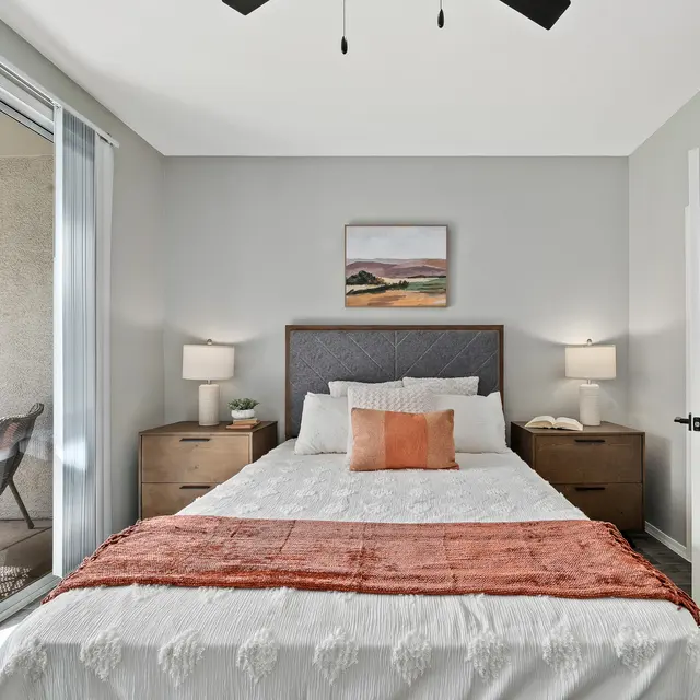 Spacious bedroom with modern furnishings, ceiling fan, and private patio access at Bear Canyon Apartments