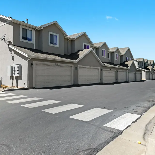 Row of Residential Homes A row of residential homes with garages on the ground level, featuring light-colored facades under a clear blue sky.
