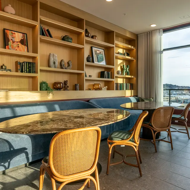 A modern interior space featuring built-in bookshelves, a circular marble table, and stylish seating with a view.