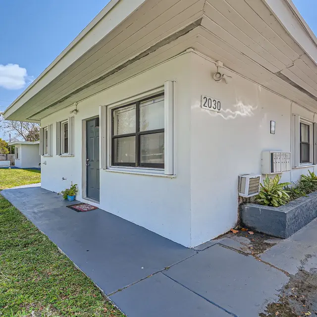 Exterior view of a single-story white house with a small garden in front.