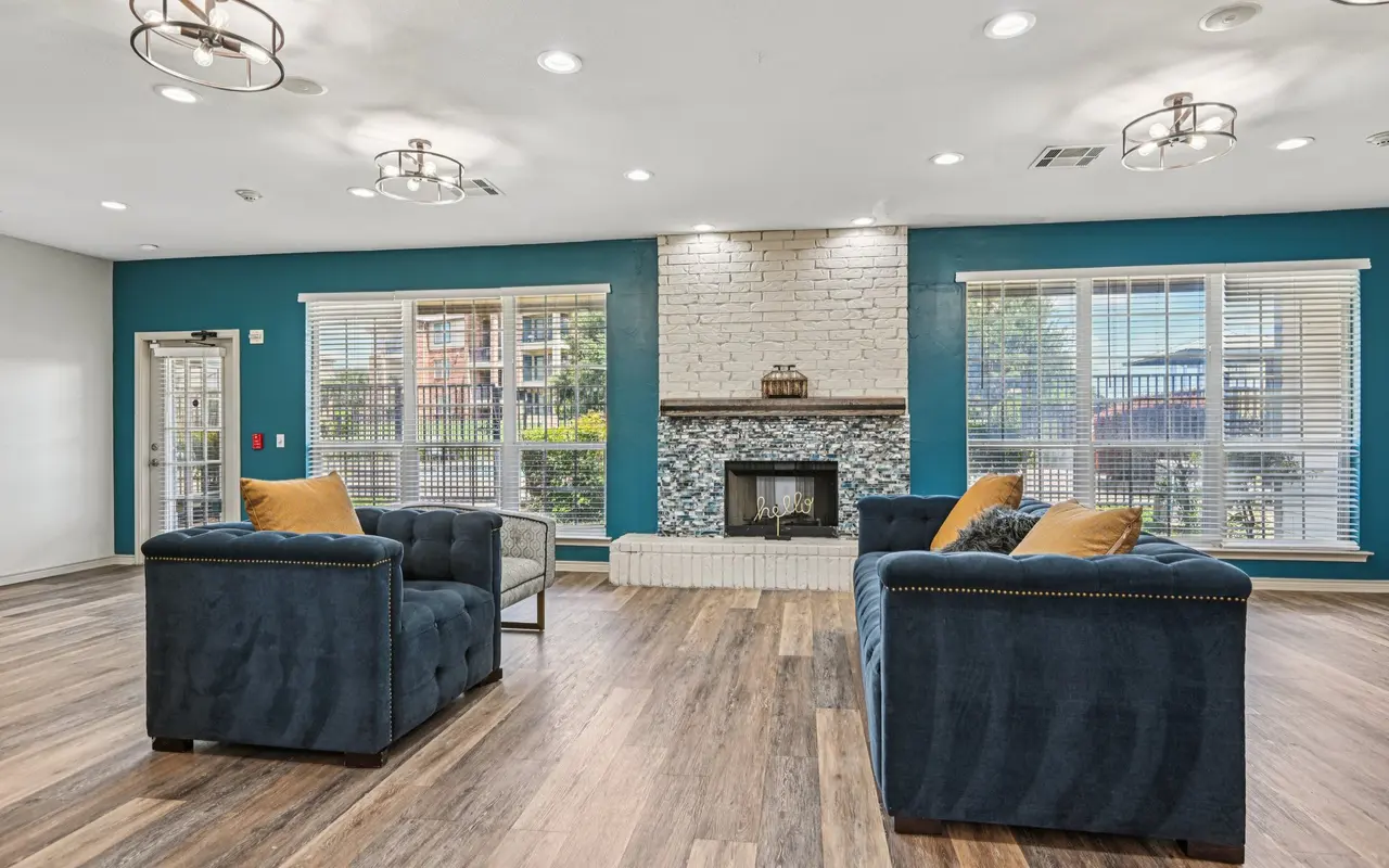 Cozy living room featuring two blue sofas with yellow cushions, a fireplace, and large windows.