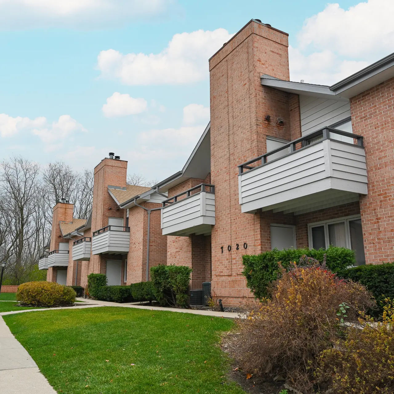 Exterior view of a brick apartment complex with greenery and a pathway