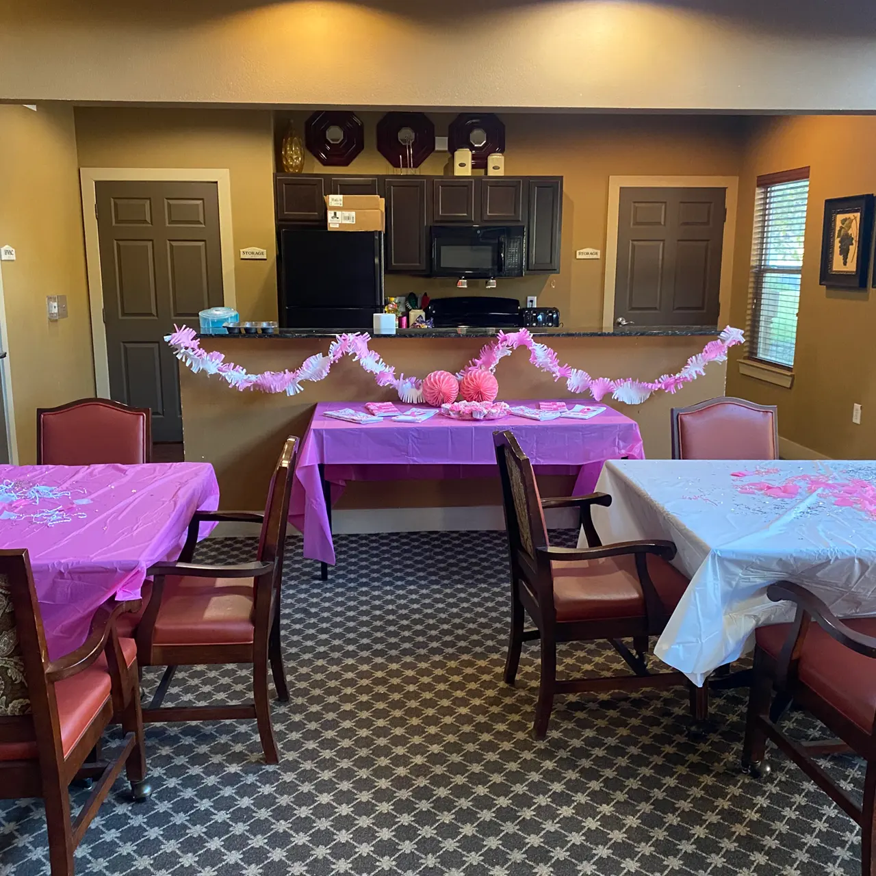 A decorated room featuring tables with pink tablecloths, a white tablecloth, and festive decorations.