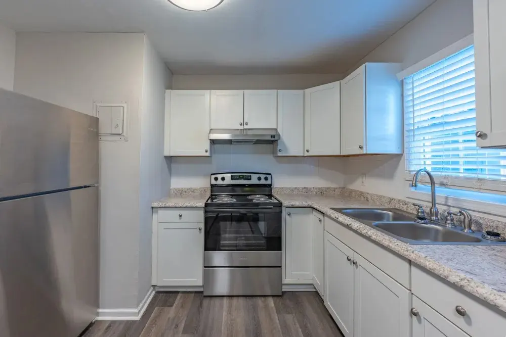 A modern kitchen featuring stainless steel appliances, white cabinetry, and granite countertops.
