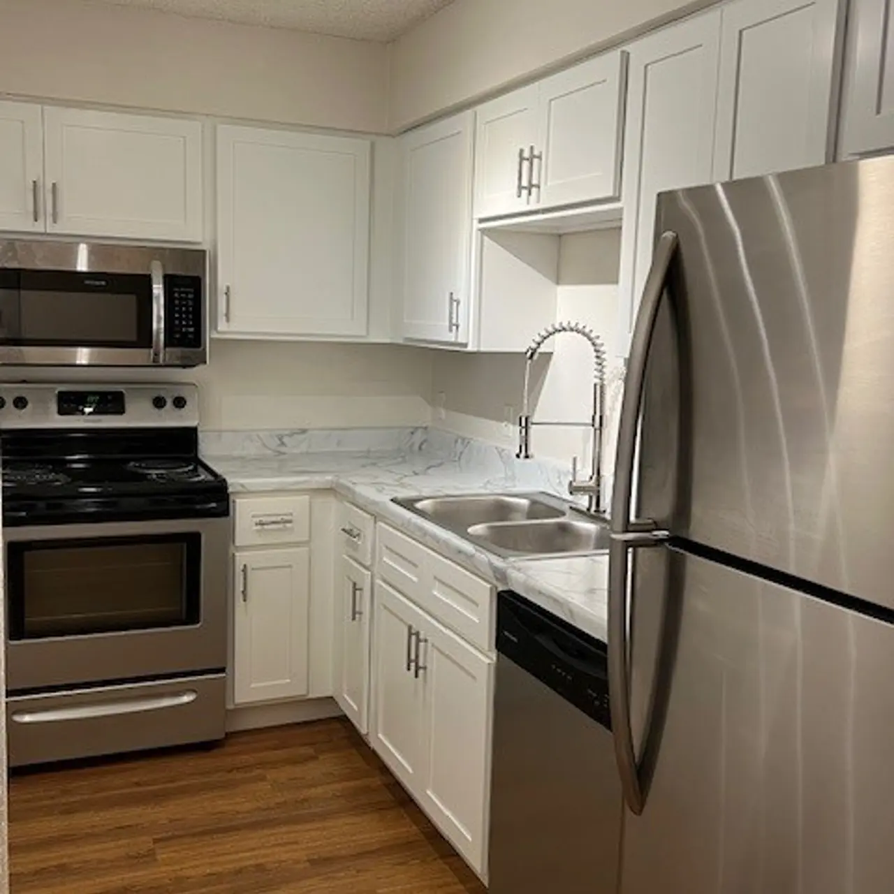Modern Kitchen Design A modern kitchen featuring white cabinetry, stainless steel appliances, and a wood-like floor.